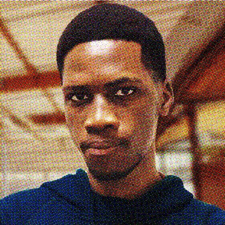 Ian Wright2 A man stares intently into the camera. He wears a blue shirt. You see the ceiling behind him. The picture is pixelated.